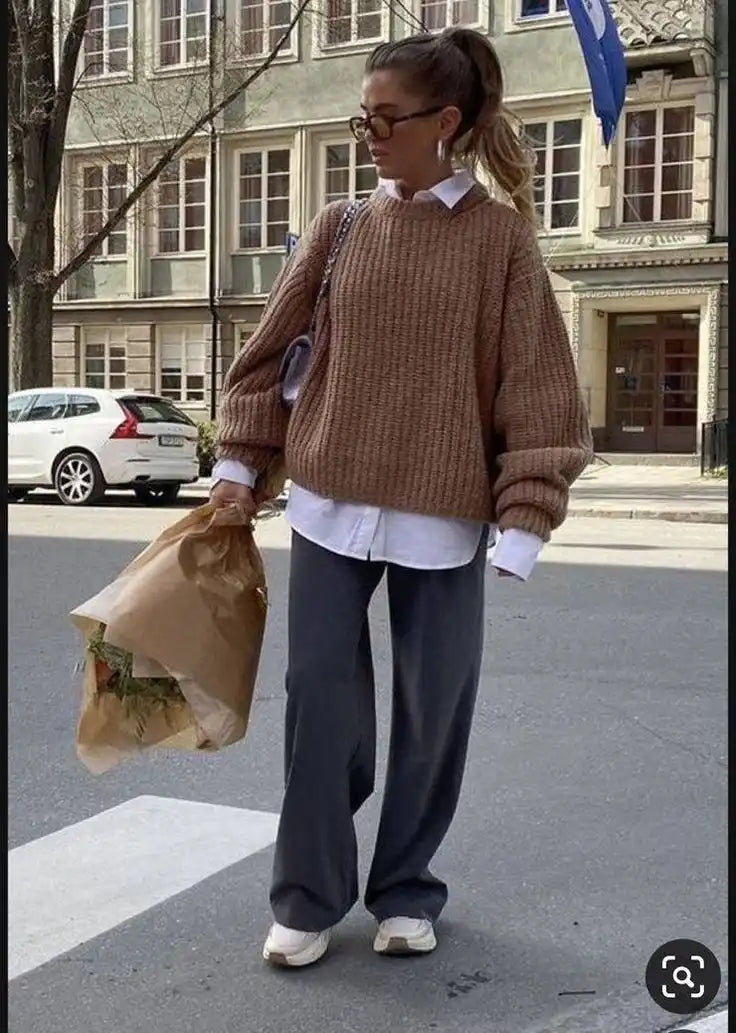 Femme portant un pull brun surdimensionné et un pantalon gris.